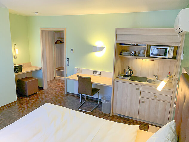 Blick auf Kitchinette, Esstisch und Schribtisch mit Tresor