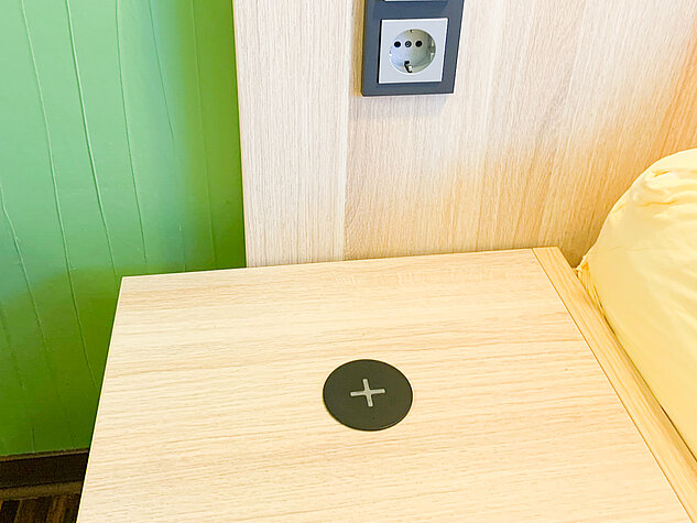 QI-Lader für Handy und zentraler Lichtschalter am Bett