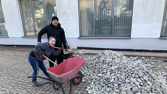 Sarah Spahn und Chaowalit Naboon helfen mit dem Kies