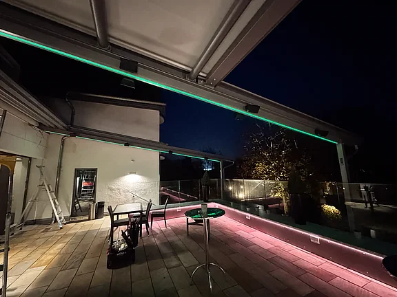 Farbiges LED-Licht an Träger der Markise und unter der Bank auf der Terrasse