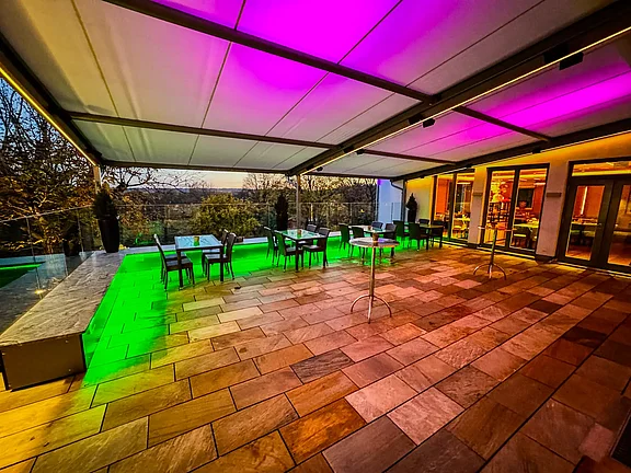 Terrasse in farbigen LED-Licht auf Markise und Sitzbank
